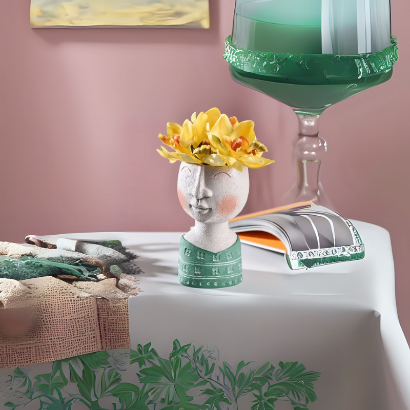 Whimsical ceramic vase with a serene face and yellow floral crown on a decorated tabletop – styled by The Niomi